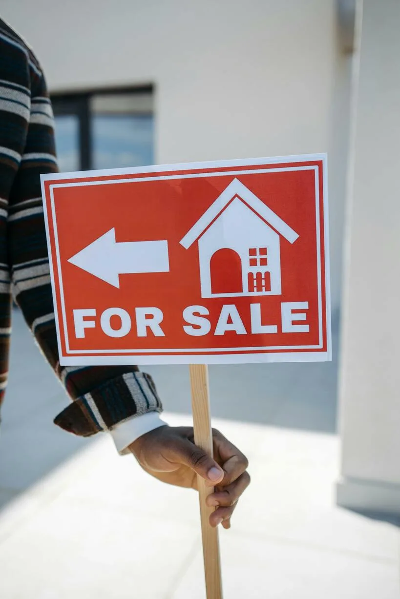 Hand holding a For Sale sign